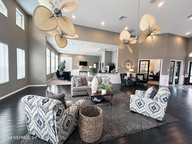 living room featuring a towering ceiling, ceiling fan, and dark wood-type flooring