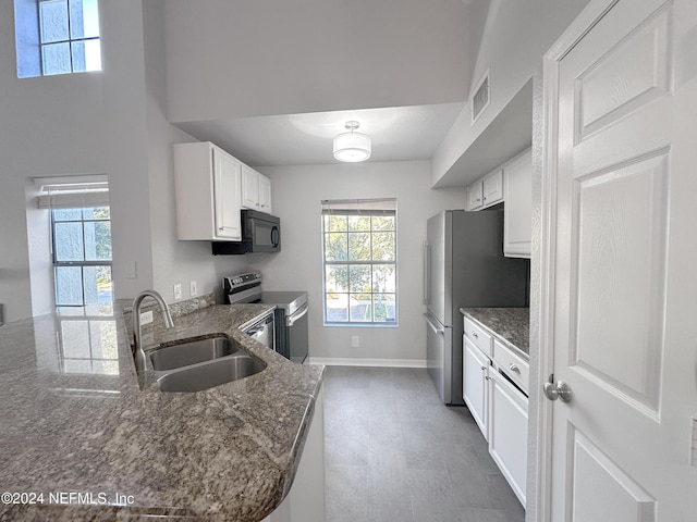 kitchen with kitchen peninsula, sink, white cabinetry, and stainless steel appliances