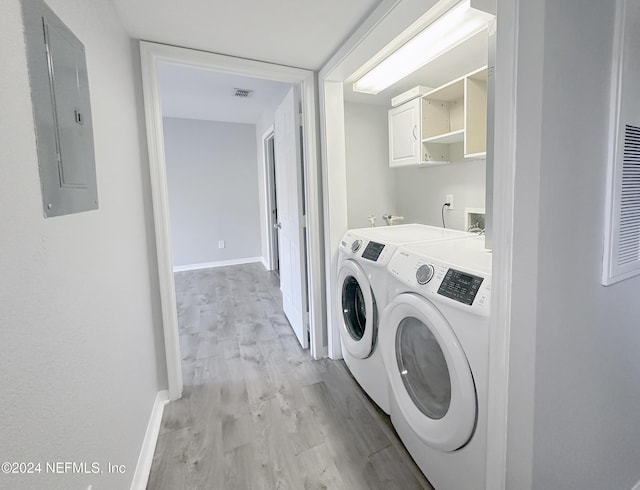 washroom featuring washer and dryer, light hardwood / wood-style floors, and electric panel