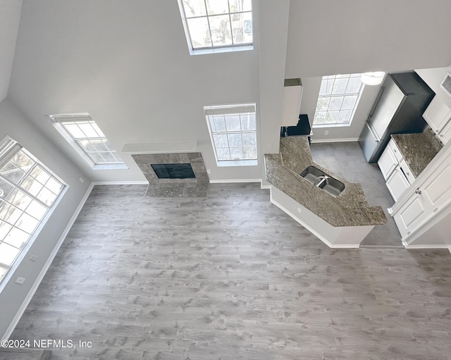 unfurnished living room featuring hardwood / wood-style flooring, a towering ceiling, and sink