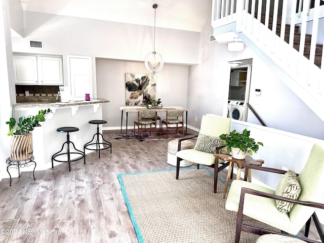 interior space featuring light wood-type flooring, a high ceiling, and washer / clothes dryer