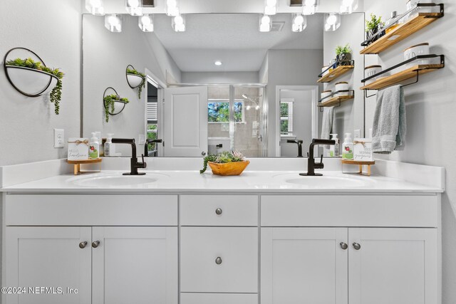 bathroom featuring a textured ceiling, vanity, and a shower with shower door