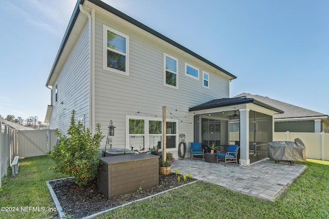 back of property featuring a lawn, a sunroom, ceiling fan, and a patio