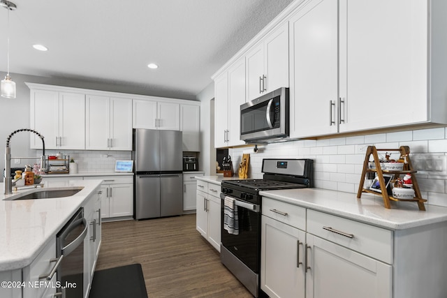 kitchen with appliances with stainless steel finishes, dark hardwood / wood-style flooring, sink, decorative light fixtures, and white cabinets