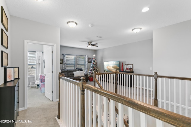 hallway with light carpet and a textured ceiling