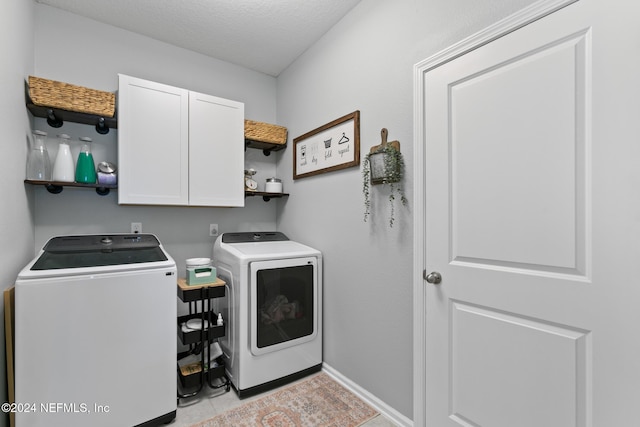 laundry room featuring cabinets, a textured ceiling, washing machine and dryer, and light tile patterned floors