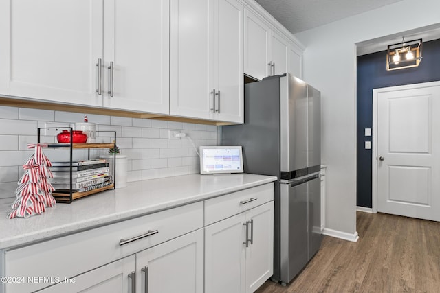 kitchen with white cabinetry, stainless steel fridge, a textured ceiling, decorative backsplash, and hardwood / wood-style flooring