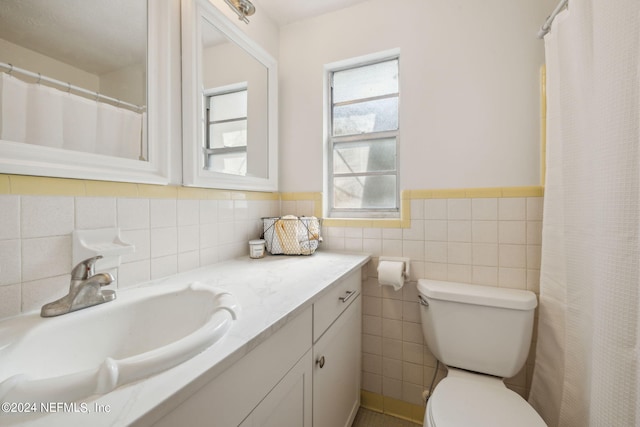 bathroom with vanity, toilet, and tile walls