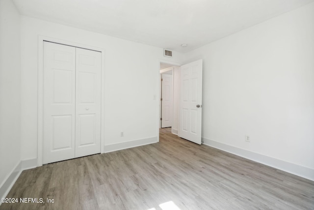 unfurnished bedroom featuring light hardwood / wood-style floors and a closet