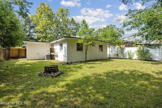 back of property with a lawn and central AC