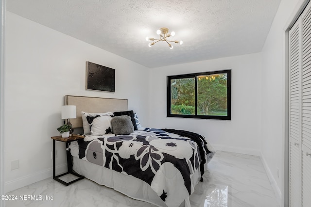 bedroom with a notable chandelier, a textured ceiling, and a closet