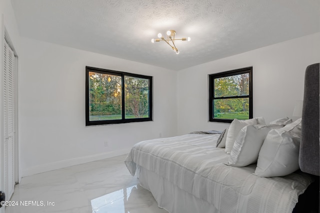 bedroom featuring a chandelier, a textured ceiling, and a closet