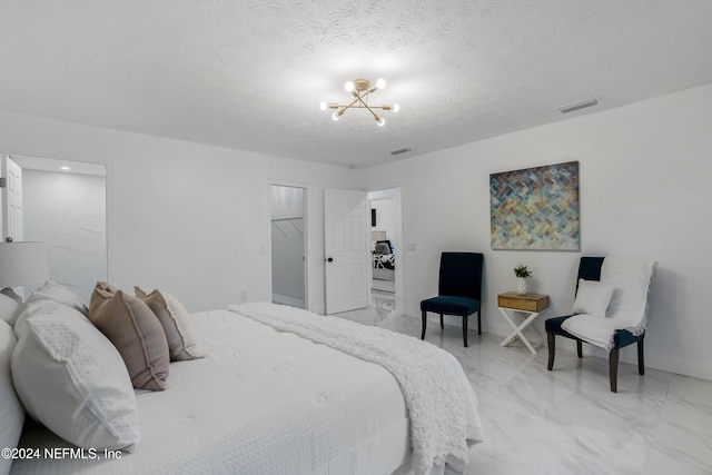 bedroom with a spacious closet, a closet, a textured ceiling, and an inviting chandelier