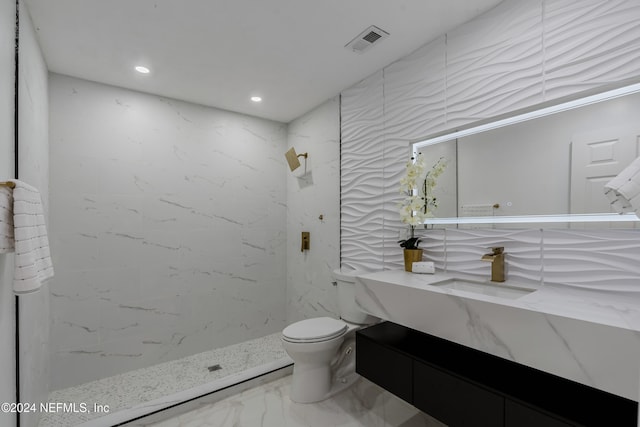 bathroom with a tile shower, vanity, and toilet