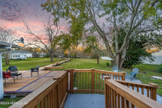 deck at dusk featuring a yard