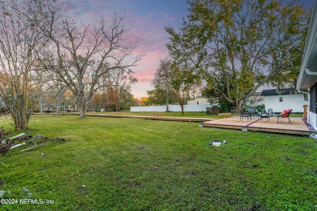 yard at dusk featuring a wooden deck