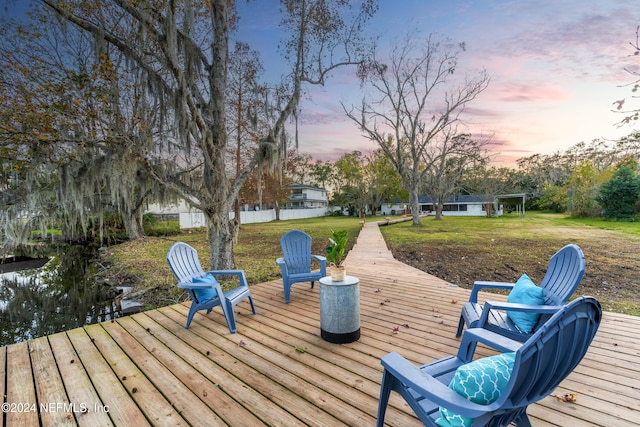 deck at dusk featuring a lawn