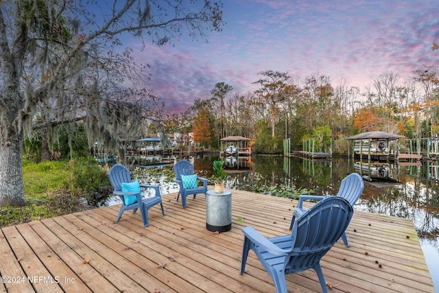 deck at dusk with a dock and a water view