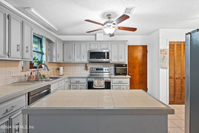 kitchen with sink, stainless steel appliances, gray cabinets, decorative backsplash, and light tile patterned floors