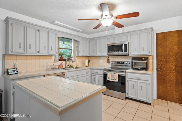 kitchen with tile counters, decorative backsplash, sink, and appliances with stainless steel finishes