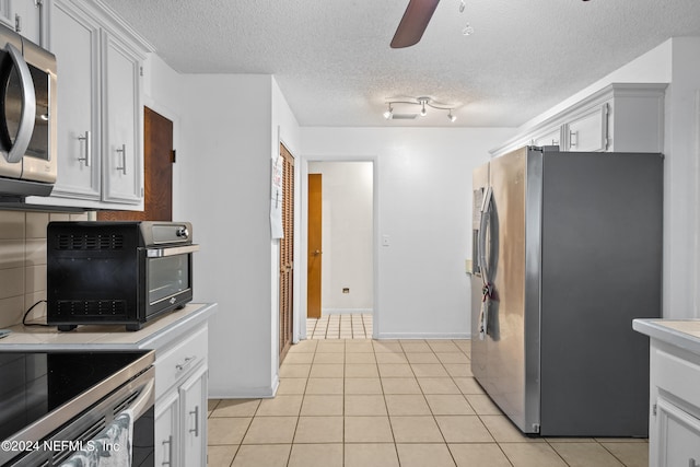 kitchen featuring light tile patterned floors, a textured ceiling, stainless steel appliances, and ceiling fan