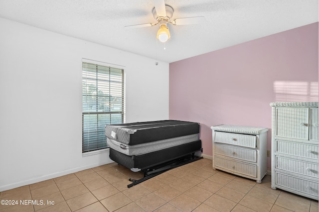 bedroom featuring light tile patterned floors, a textured ceiling, and ceiling fan