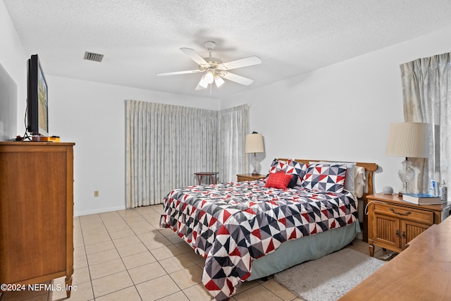 bedroom featuring ceiling fan, light tile patterned flooring, and a textured ceiling