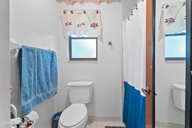 bathroom with tile patterned flooring, a shower with shower curtain, and toilet