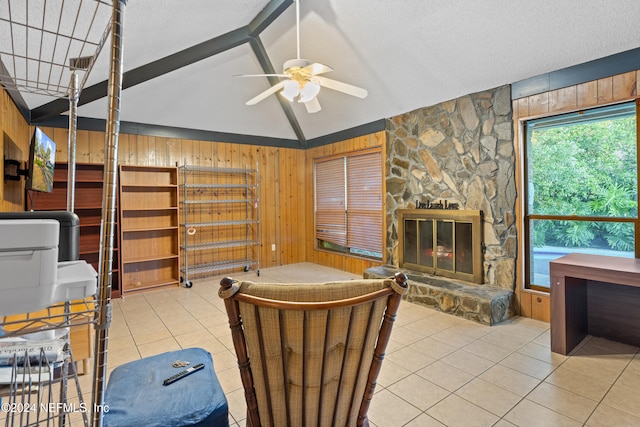 tiled living room with wooden walls, vaulted ceiling, ceiling fan, a textured ceiling, and a fireplace