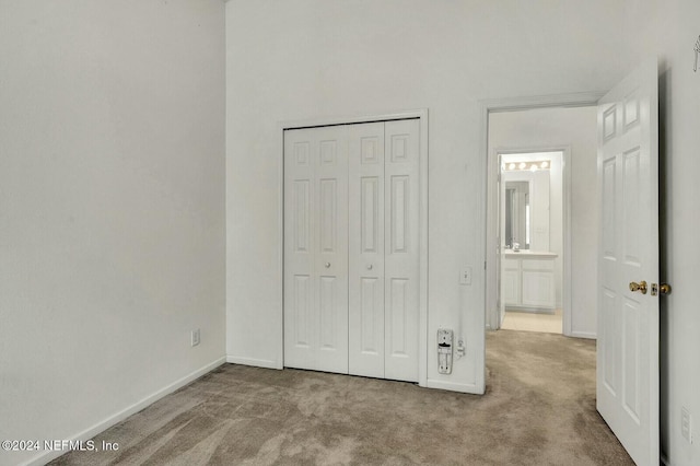 unfurnished bedroom featuring light colored carpet and a closet