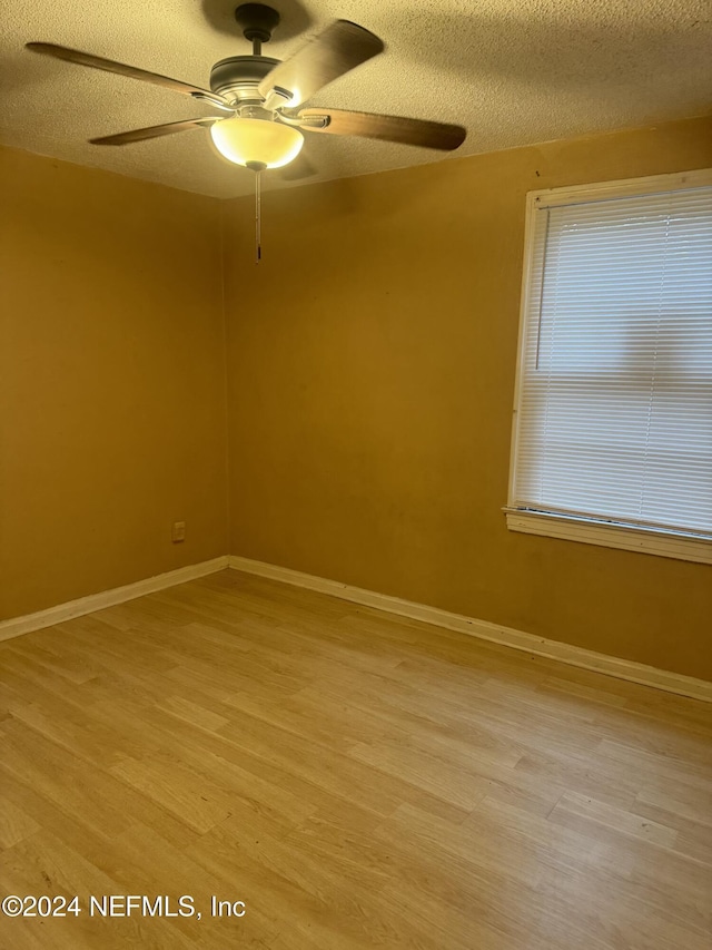 unfurnished room featuring a textured ceiling, light hardwood / wood-style floors, and ceiling fan