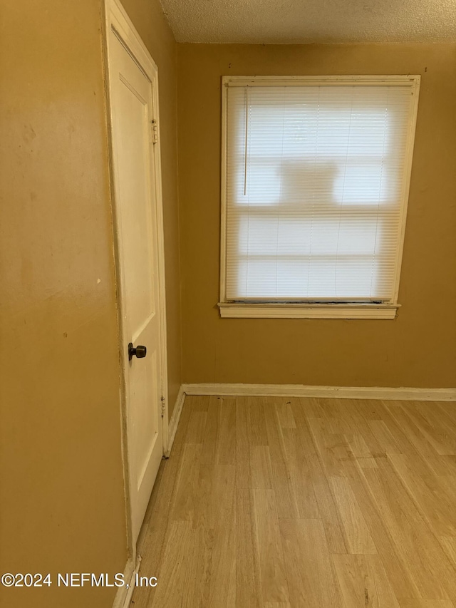 spare room with a textured ceiling and light wood-type flooring