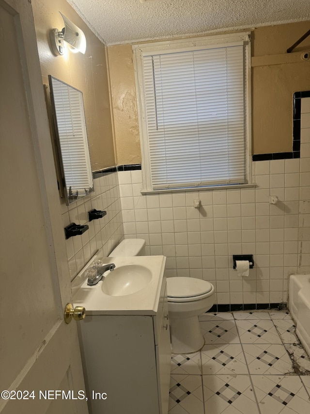 bathroom featuring tile patterned flooring, a textured ceiling, vanity, and tile walls