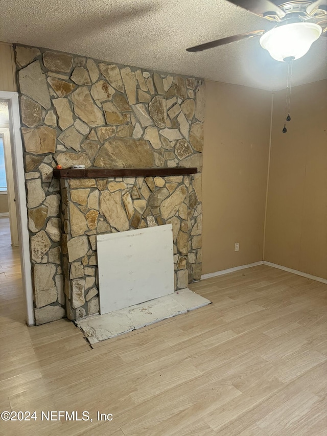 interior details with hardwood / wood-style floors, a stone fireplace, and a textured ceiling