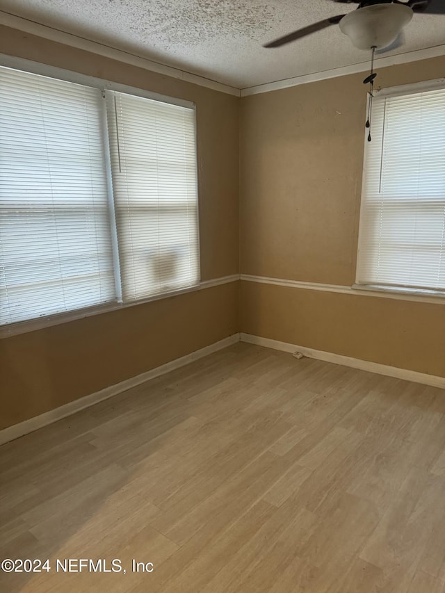 empty room with ceiling fan, light hardwood / wood-style floors, crown molding, and a textured ceiling