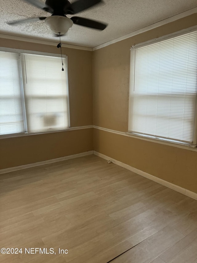 unfurnished room featuring a textured ceiling, crown molding, and light hardwood / wood-style flooring