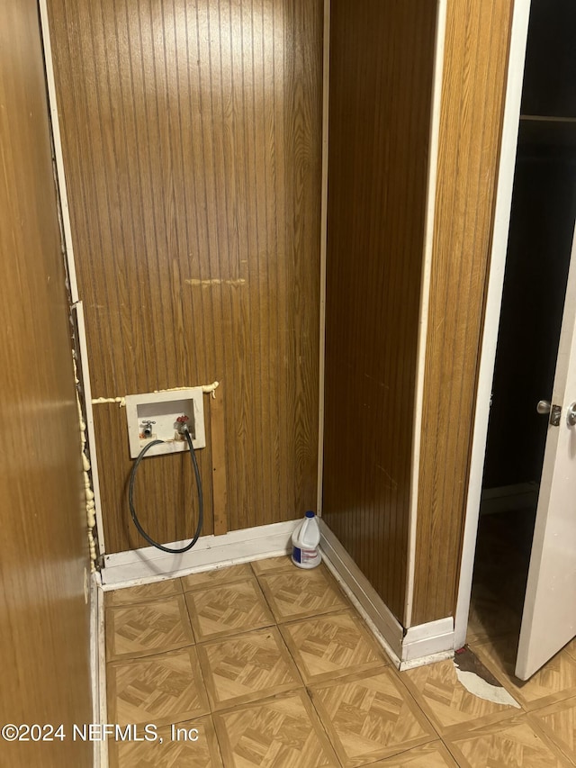 clothes washing area with wood walls, hookup for a washing machine, and parquet floors