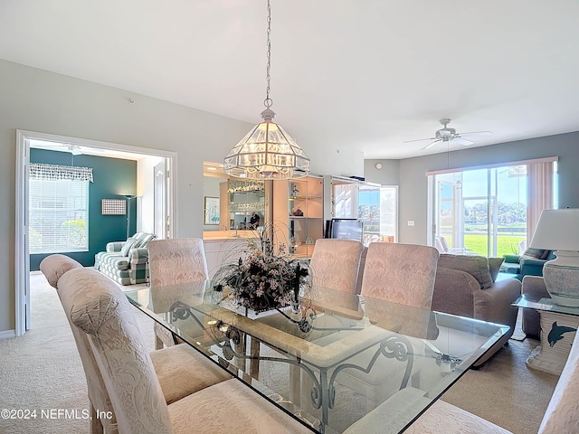 carpeted dining space featuring ceiling fan with notable chandelier