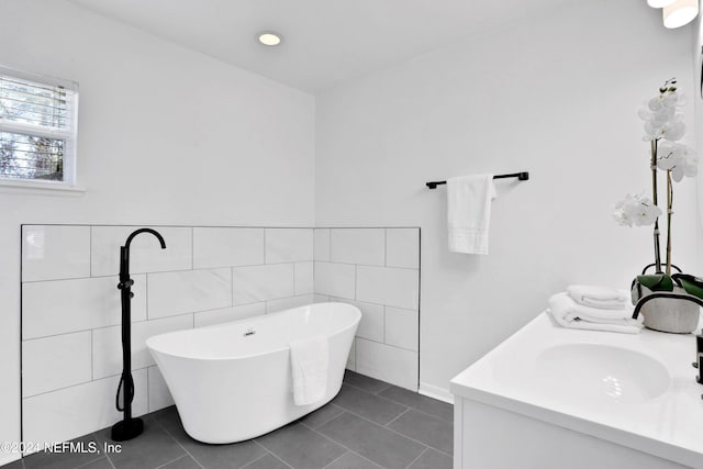 bathroom featuring tile patterned floors, a bathtub, vanity, and tile walls