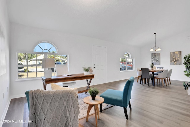 interior space featuring wood-type flooring, lofted ceiling, and an inviting chandelier