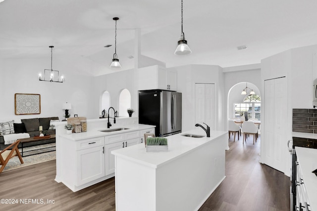 kitchen featuring stainless steel fridge, a center island with sink, decorative light fixtures, and sink