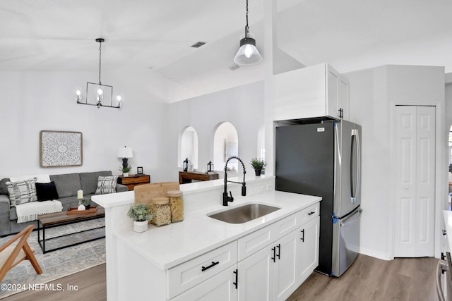 kitchen with white cabinetry, sink, pendant lighting, vaulted ceiling, and light wood-type flooring