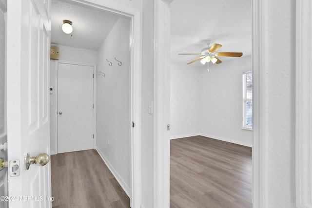 hall featuring light hardwood / wood-style floors and a textured ceiling