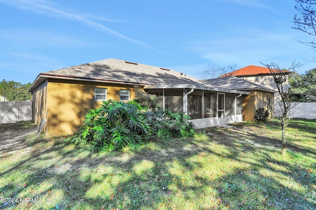 back of property featuring a sunroom and a lawn