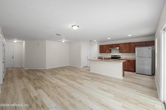 kitchen featuring light stone countertops, sink, an island with sink, light hardwood / wood-style floors, and appliances with stainless steel finishes