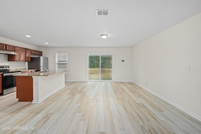 kitchen with a kitchen island with sink, light hardwood / wood-style flooring, appliances with stainless steel finishes, light stone counters, and a breakfast bar area