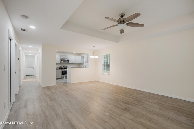 unfurnished living room featuring ceiling fan with notable chandelier, light hardwood / wood-style flooring, and sink