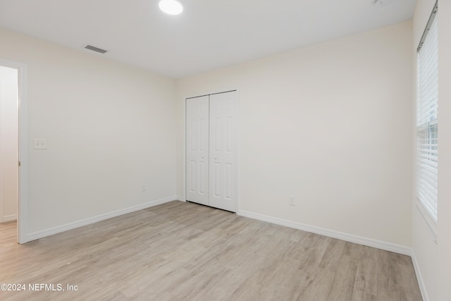 unfurnished bedroom with a closet and light hardwood / wood-style flooring