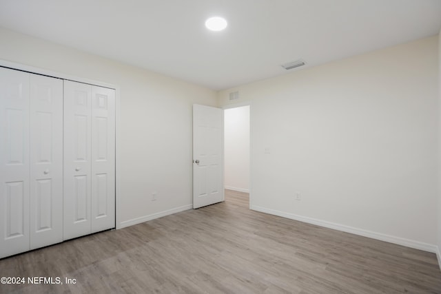 unfurnished bedroom with light hardwood / wood-style flooring and a closet