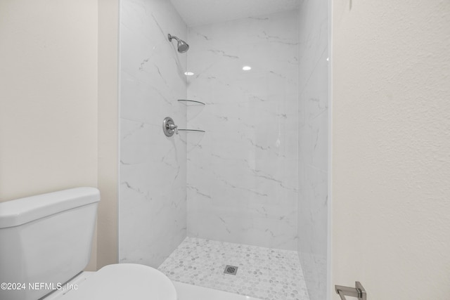 bathroom with a tile shower and toilet